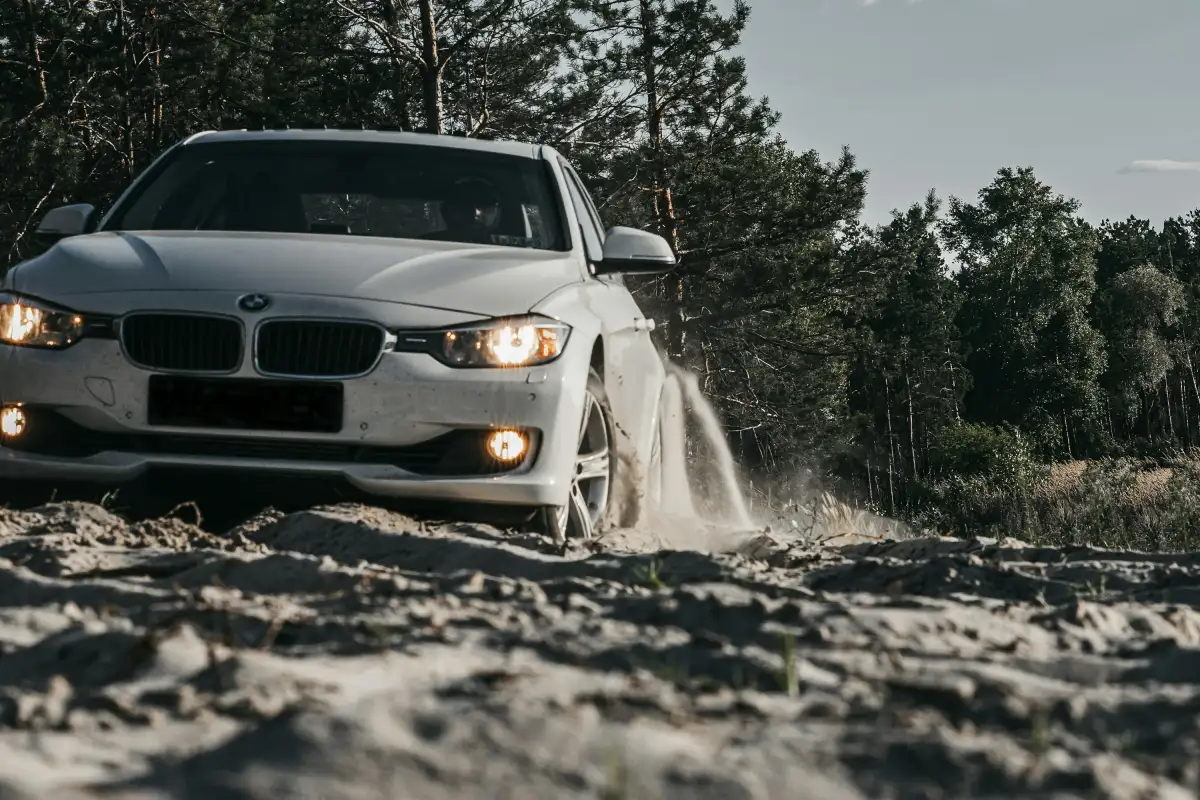 white BMW car on dirt road